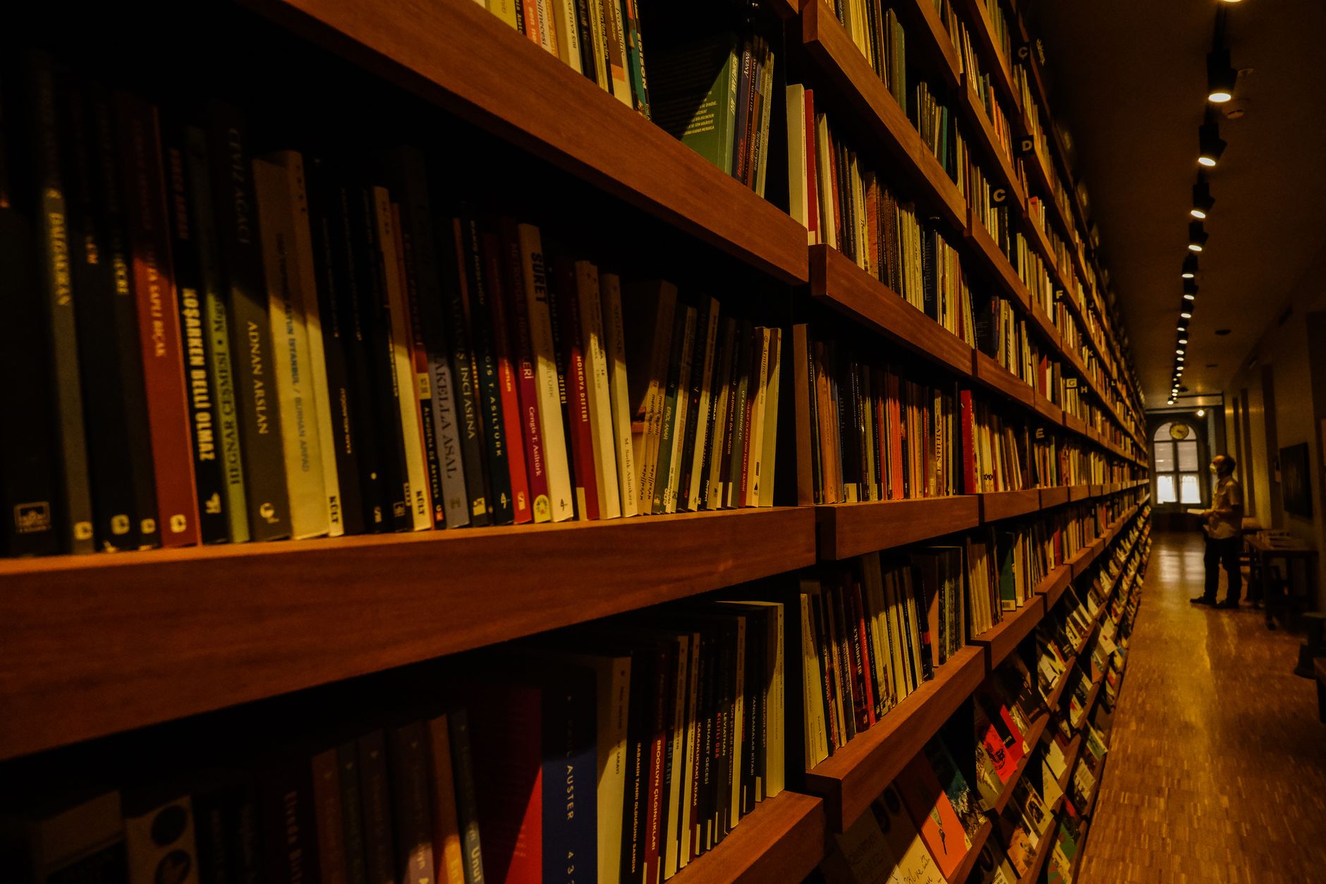 Long corridor of library bookshelves with warm overhead lighting