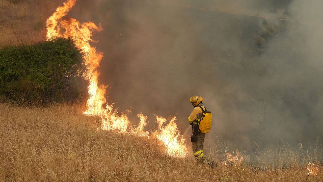Dense wildfire smoke rising over a dry European hillside landscape