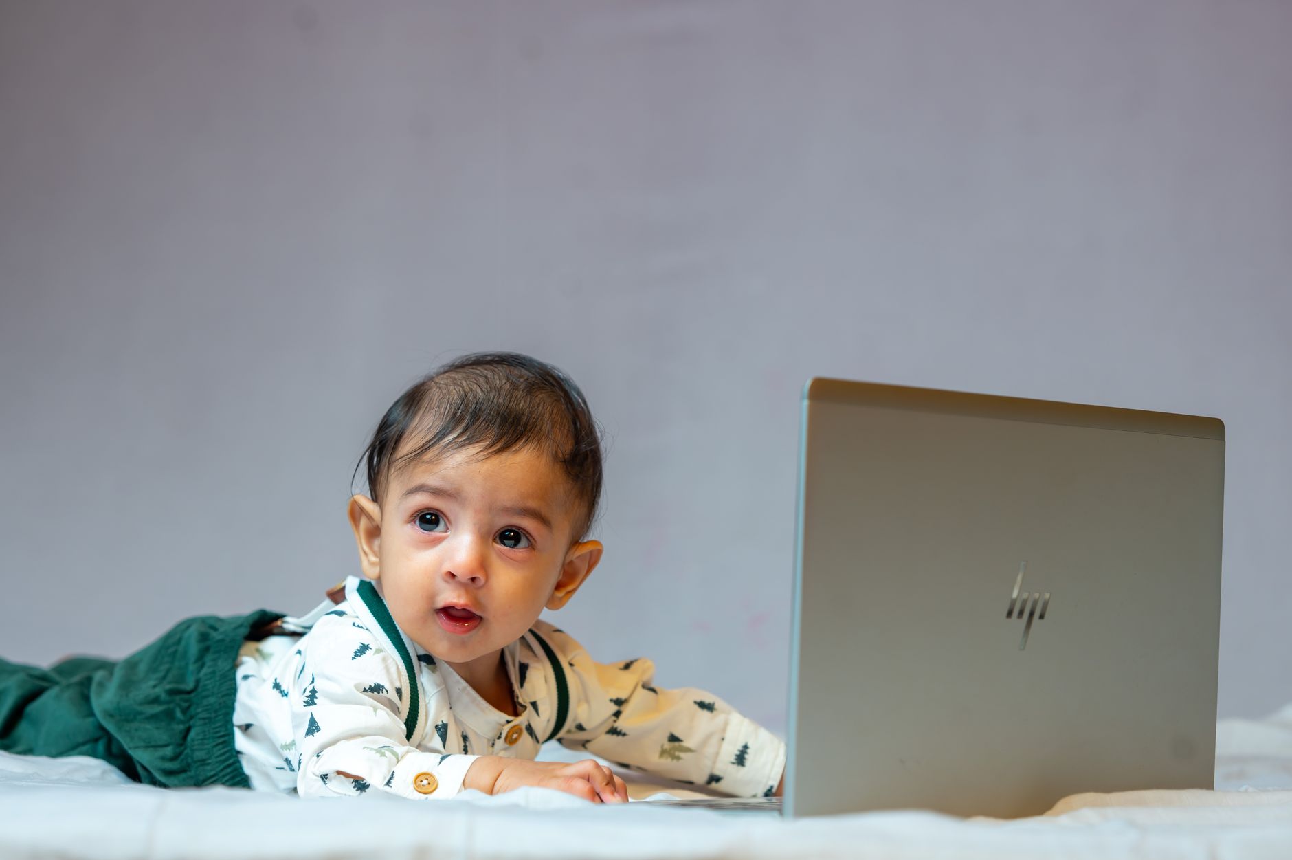 Young child using a laptop while lying on a couch, device resting on abdomen