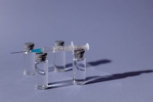 A COVID-19 vaccine vial and syringe on a medical surface