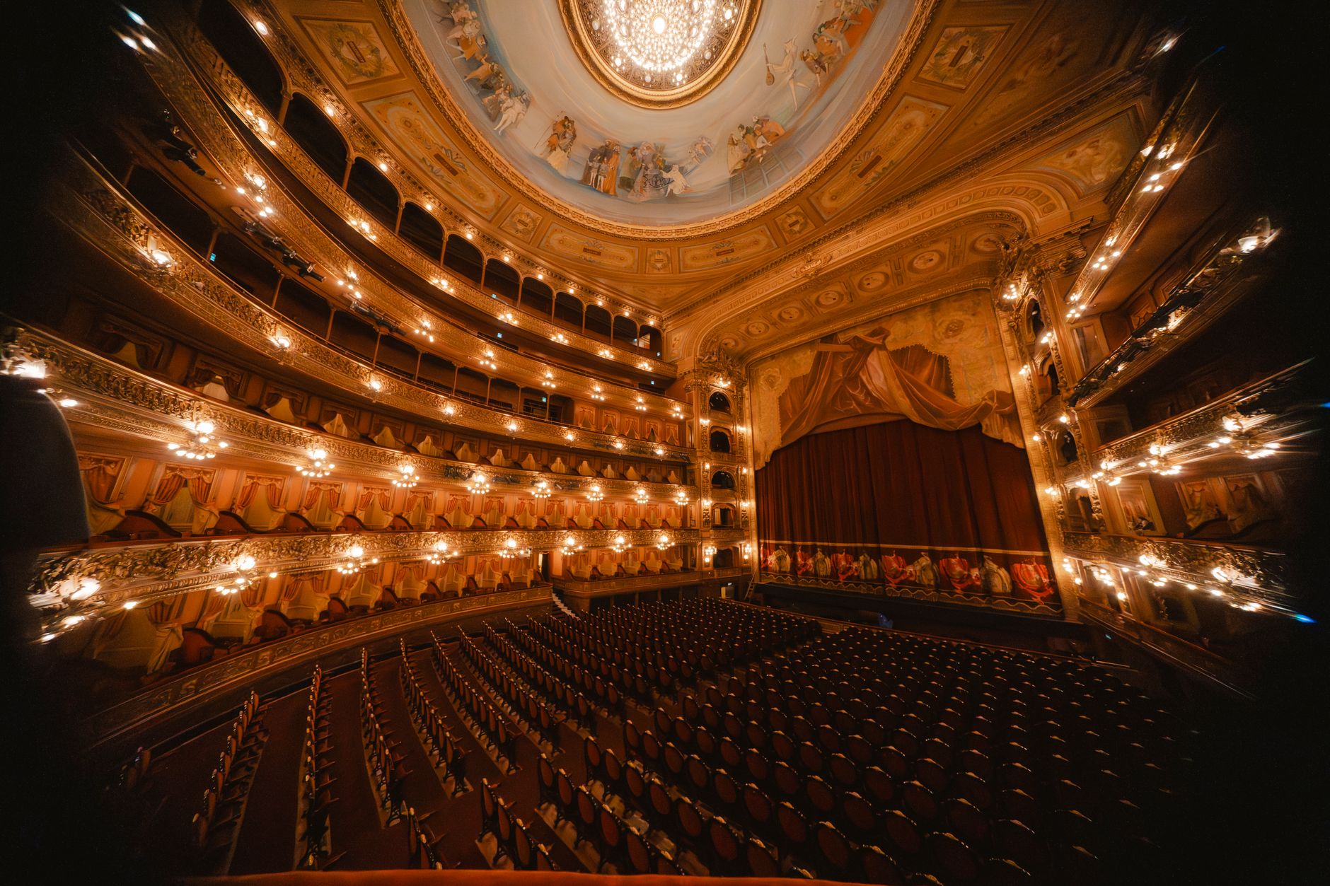 An ornate opera house stage with dramatic lighting and empty red seats
